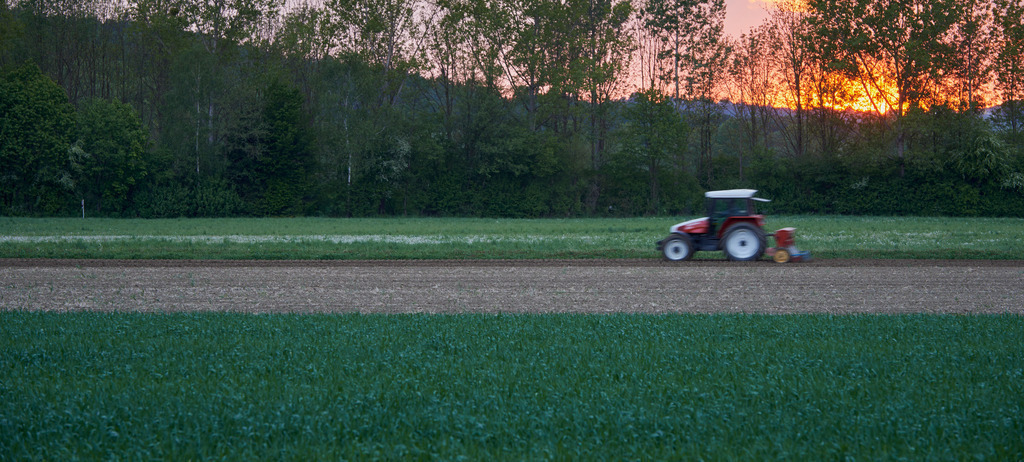 Roter Traktor bei Feldarbeit | Rauchwart, Austria - May 07, 2016: Roter Traktor bei Feldarbeit im Sonnenuntergang. - Realisiert mit Pictrs.com