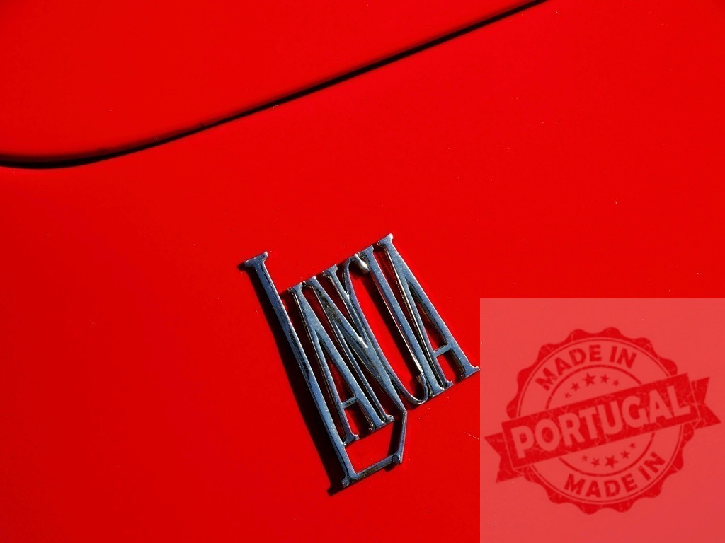 Lancia chrome car emblem on red paint | Lancia chrome car emblem reflecting light on a bright red car body - Realized with Pictrs.com
