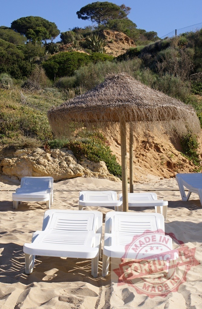 Beach sand with sun loungers and straw umbrella | Sun loungers on sandy beach with straw umbrella under clear blue sky, backed by a vegetated cliff - Realized with Pictrs.com