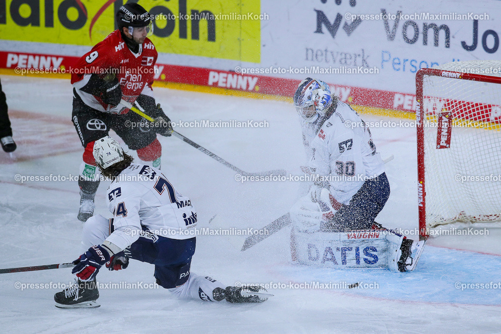 KoeDEL08032401040 | 08.03.2024, Köln, Eishockey, Penny DEL, 52. Spieltag, Lanxess-Arena, Kölner Haie - Adler Mannheim: Ryan MacInnis (Adler Mannheim) und Torhüter Arno Tiefensee (Adler Mannheim) verteidigen das Tor gegen Maximilian Kammerer (Kölner Haie)