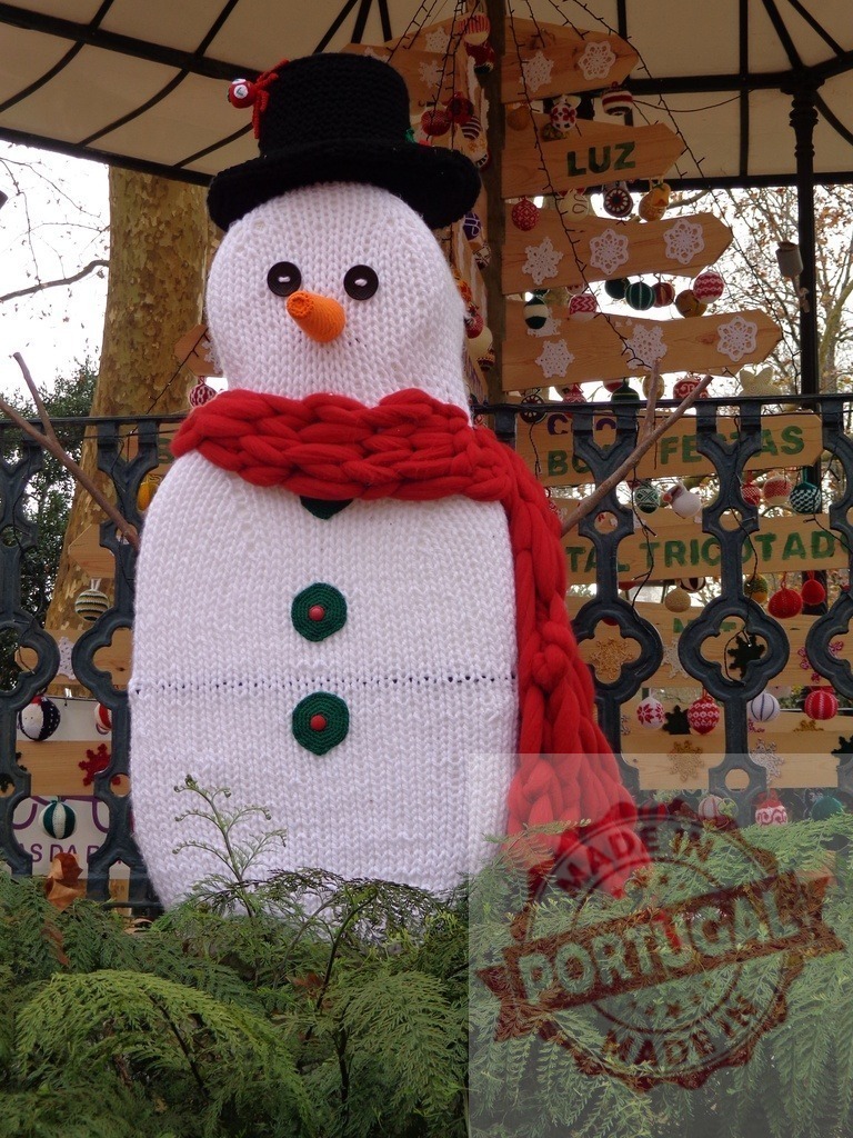Knitted snowman celebrating Christmas with a handmade wooden tree and colorful ornaments | Large, knitted snowman stands proudly in front of a handmade wooden Christmas tree adorned with colorful ornaments, celebrating the festive season - Realisiert mit Pictrs.com