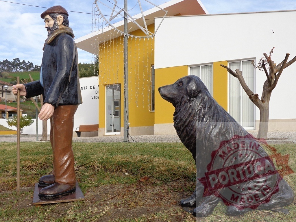 Shepherd and dog statues standing on grass in front of building | Shepherd statue holding walking stick and looking at sitting dog statue - Realized with Pictrs.com