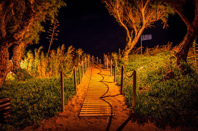 2026-07-24_20-45-46_640 | Mystischer Sandweg, beleuchtet von orangen Lichtern, umgeben von Bäumen und Dunkelheit, Heraklion, Kreta, Griechenland - Realisiert mit Pictrs.com
