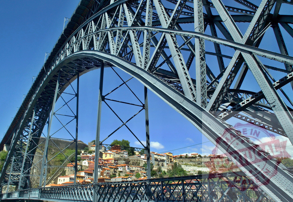 Dom Luís I Bridge arch structure spanning Porto cityscape | Dom Luís I Bridge iron structure frames the historic city skyline against a clear blue sky - Realisiert mit Pictrs.com