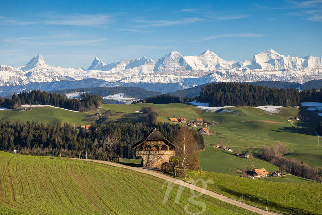 traditional wooden farm house in Emmental in spring in front of the Bernese Alps | Die ideale Geschenkidee für Naturliebhaber. Naturbilder von Marcel Gross Photography für ihr Zuhause in den verschiedensten Formaten und Materialien. - Realisiert mit Pictrs.com