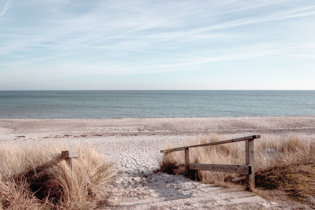 Wandbild: Treppe ans Meer | Dieses Wandbild im Querformat zeigt eine Treppe, die an den Strand führt. Auf der linken und rechten Seite der Treppe wachst Strandgras. Ein Wandbild, welches zum Träumen einlädt. Holen Sie sich diesen traumhaften Strand auf Leinwand, Aluminium-Platte oder als Glasbild. Ideal fürs Wohnzimmer, Schlafzimmer, Küche, den Arbeitsplatz oder die Ferienwohnung. Die Wandbilder werden individuell für Sie in vielen Abmessungen produziert. - Realisiert mit Pictrs.com