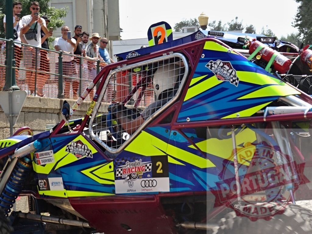 Buggy driver racing in urban environment during competition with spectators taking pictures | Professional buggy driver racing on a colorful vehicle in an urban environment with people watching and taking pictures - Realisiert mit Pictrs.com
