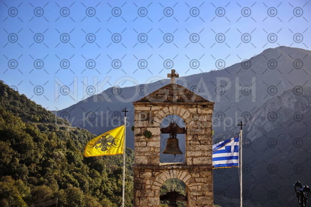 Flaggen am Kloster Giroméri - Iera Moni Giromeriou | Die Flagge der griechisch-orthodoxen Kirche und die Nationalflagge Griechenlands rahmen den Glockenturm am Koster Giroméri vor der Bergkulisse Nordgriechenlands ein. Das Kloster „Iera Moni Giromeriou“ liegt in der Präfektur Thesprotia im Nordwesten von Griechenland, rund acht Kilometer von der Stadt Filiates entfernt. Auf der Bergkette Farmakovouni wurde das Kloster Anfang des 14. Jahrhunderts auf einer Höhe von rund 300 Metern gegründet.