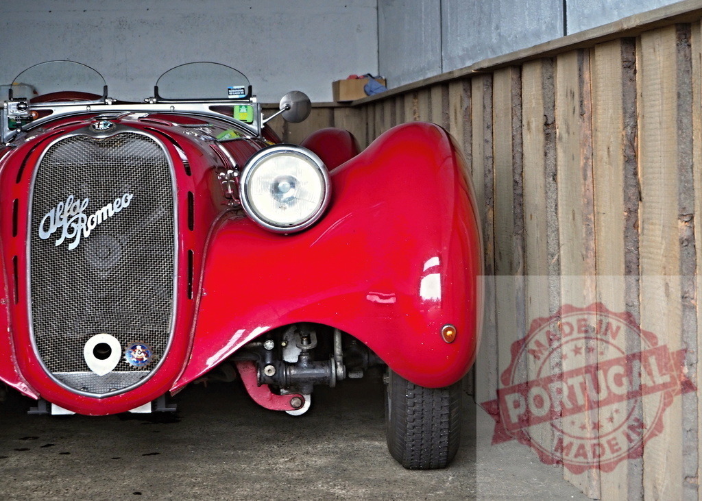Alfa Romeo vintage sports car parked in garage | Red Alfa Romeo classic car parked in a rustic garage with wooden walls - Realisiert mit Pictrs.com