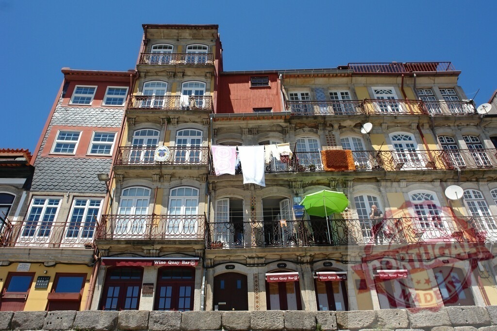 Porto Ribeira colorful historic buildings with laundry hanging. Porto - Portugal | Colorful old town buildings in Ribeira with laundry drying on balconies under a clear sky - Realized with Pictrs.com