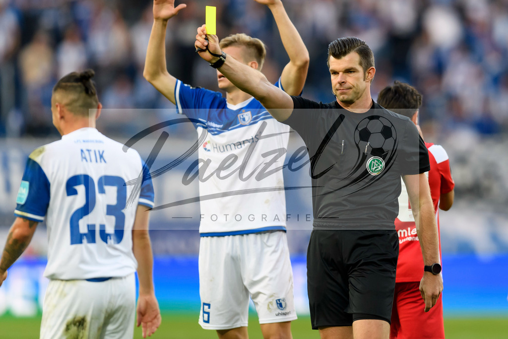 FCMFCK20210904_186 | Fussball, Herren: Schiedsrichter Alexander Sather zeigt Barıs Atik (1. FC Magdeburg) die gelbe Karte beim Spiel der 3. Liga zwischen 1. FC Magdeburg und 1. FC Kaiserslautern in der MDCC-Arena am 04.09.2021 in Magdeburg, Deutschland.DFB / DFL REGULATIONS PROHIBIT ANY USE OF PHOTOGRAPHS AS IMAGE SEQUENCES AND/OR QUASI-VIDEO. - Realisiert mit Pictrs.com