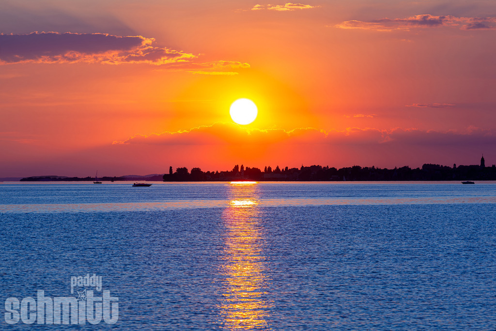 Sonnenuntergang bei der Insel Lindau am Bodensee | Die untergehende Sonne taucht den Bodensee bei der Insel Lindau in warmes, goldenes Licht. Über dem ruhigen Wasser entsteht eine stimmungsvolle Abendkulisse, die den besonderen Charme der Lindauer Insel eindrucksvoll zur Geltung bringt. - Realisiert mit Pictrs.com