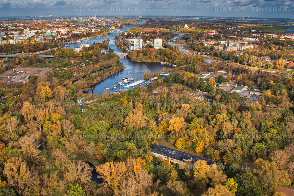 Magdeburg-Zollhafen_Rothehornpark_Haus-der-Eisenbahner_6295 | Blick aus dem Tragschrauber über den Magdeburger Stadtpark und den Zollhafen. Im Vordergrund prägen die Bäume und Grünflächen des Rotehornparks das Bild, dahinter erstreckt sich der Zollhafen mit der Magdeburger Innenstadt am Horizont.Ein heute verfallenes Gebäude ist auf dieser Aufnahme besonders interessant: das ehemalige Kulturhaus der Eisenbahner. Es gehörte über Jahrzehnte zur Geschichte der Rotehorninsel und war ein Veranstaltungs- und Kulturort. Später wurde das Gebäude aufgegeben und schließlich abgerissen. Damit dokumentiert dieses Luftbild nicht nur den heutigen Stadtpark, sondern auch ein Stück Magdeburger Stadtgeschichte, das heute so nicht mehr zu sehen ist.Gerade solche Aufnahmen zeigen, welchen Wert ein Luftbildarchiv haben kann: Was heute verschwunden ist, bleibt im Bild erhalten. - Realisiert mit Pictrs.com