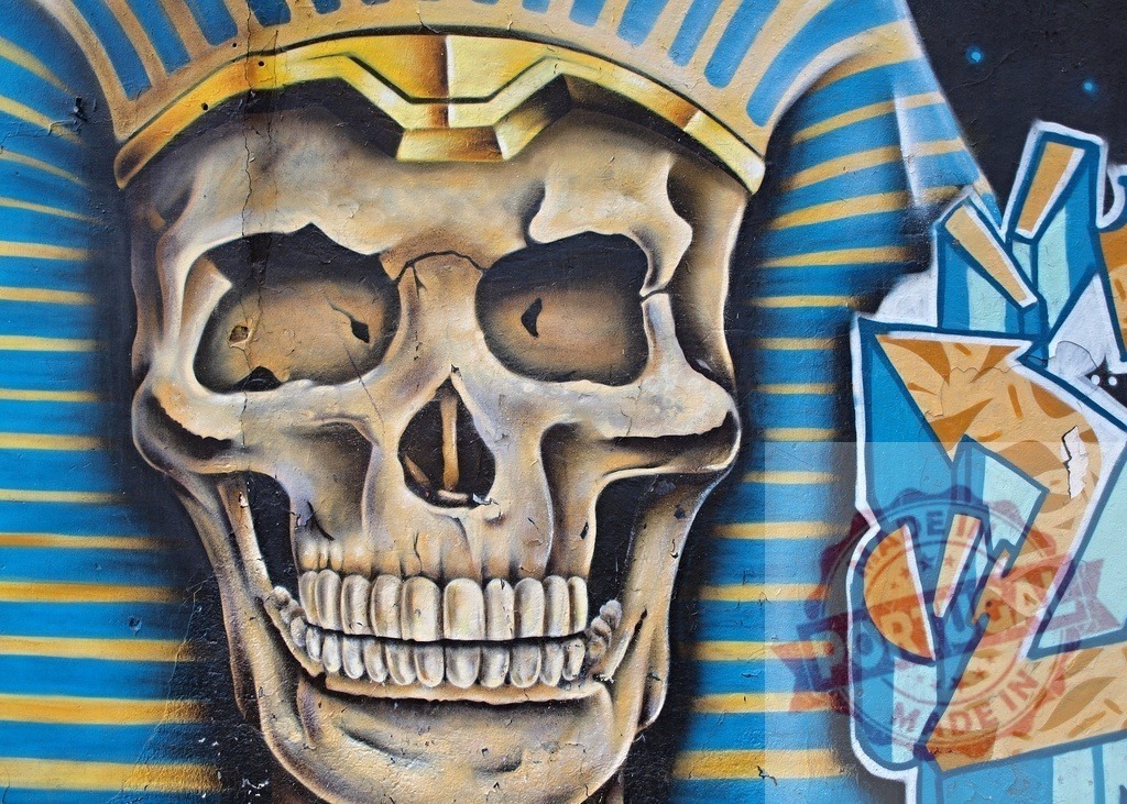 Skull wearing pharaoh headdress graffiti street art mural | Skull wearing an Egyptian pharaoh nemes crown painted as street art on a wall - Realized with Pictrs.com