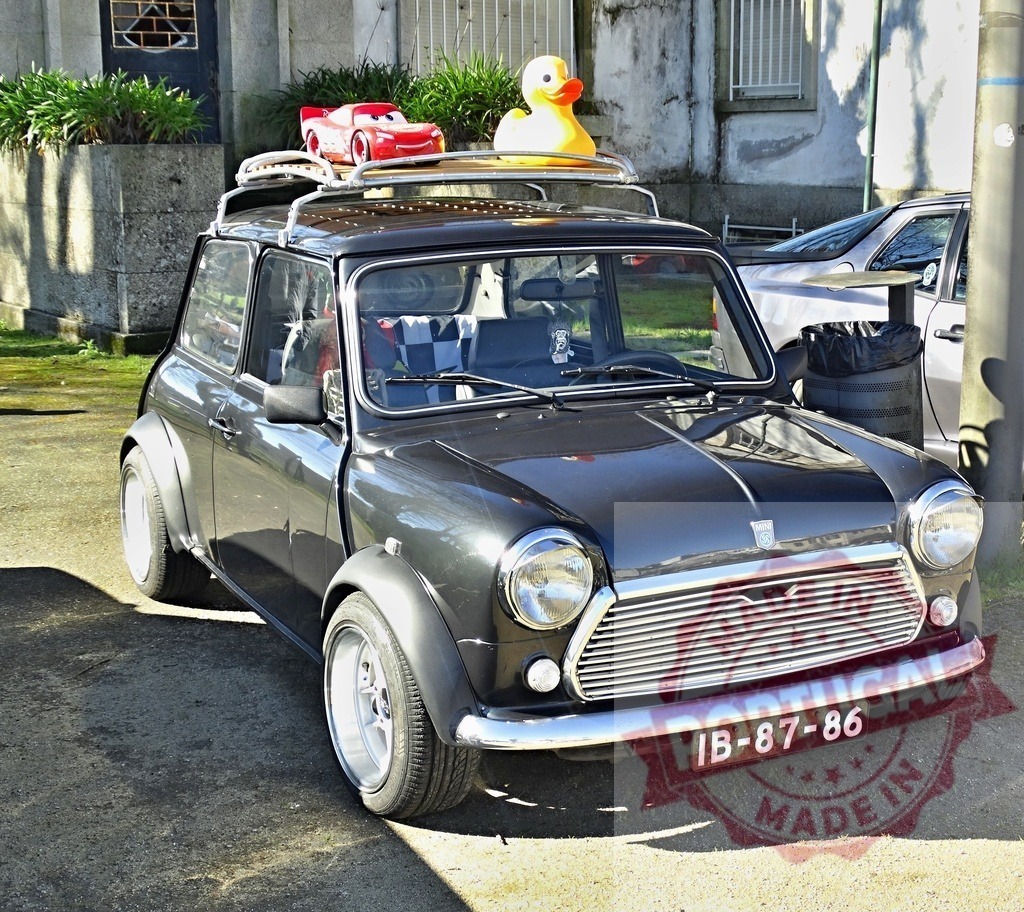 Mini Cooper classic car with roof rack and toys | Classic black Mini Cooper parked outdoors with Lightning McQueen and rubber duck on roof rack - Realized with Pictrs.com