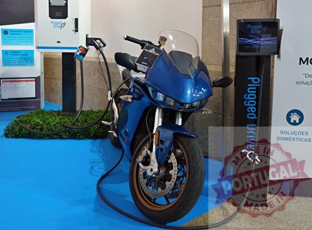 Electric motorcycle charging at public station for sustainable transport | Electric motorcycle plugging into charging station for eco-friendly power - Realisiert mit Pictrs.com