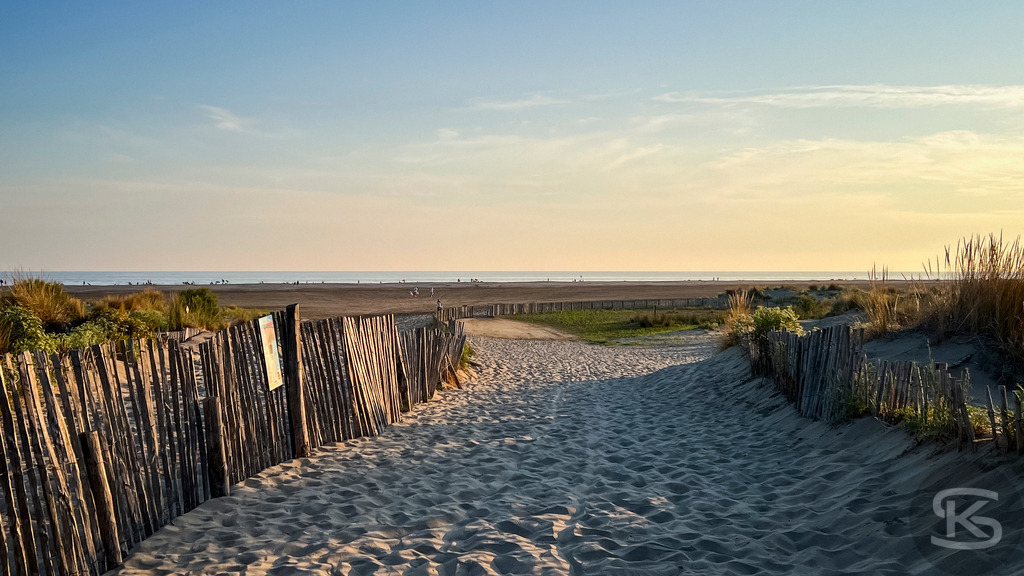 Strandweg in der Camargue – Goldenes Abendlicht am Mittelmeer | Weite Sandstrände der Camargue mit charakteristischen Ganivelles-Holzzäunen und sanften Wellen im goldenen Sonnenuntergang an der Mittelmeerküste. - Realisiert mit Pictrs.com