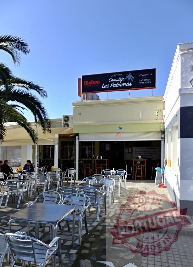 Complejo Las Palmeras cafe outdoor dining area | Cafeteria Complejo Las Palmeras with outdoor tables, chairs, and palm trees under a clear sky - Realized with Pictrs.com