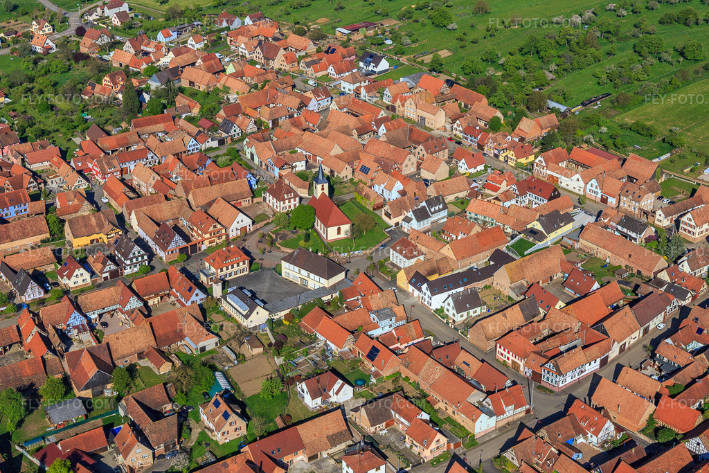 Aerial view: Village view from the east with church Uhrwiller in Uhrwiller in the state Bas-Rhin, France. – Photo: IMG_099444.jpg taken on 04/30/2017 by Werner Riehm/FLY-FOTO.com – Resolution of the original: 5331 x 3554 px