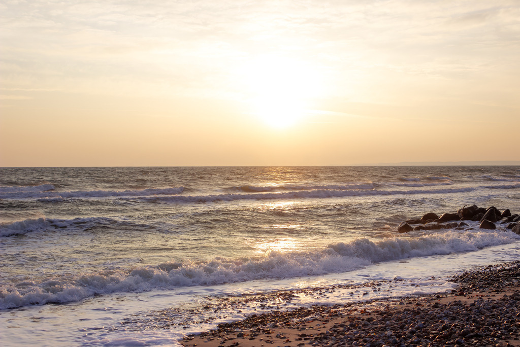Wandbild: Goldener Morgen an der Ostsee | Ein Moment voller Klarheit und neuer Energie. Dieses Wandbild fängt das erste, kostbare Licht des Tages ein, wenn die aufgehende Sonne die Ostsee in ein sanftes, goldenes Meer verwandelt. Die Silhouette der Steinmole am rechten Bildrand bricht die sanfte Brandung und gibt der unendlichen Weite eine feste Kontur. Ein Motiv, das die stille Kraft eines Erwachens an der Küste direkt in Ihr Zuhause bringt – perfekt für einen inspirierenden Start in den Tag und eine Atmosphäre voller Ruhe und Zuversicht. - Realisiert mit Pictrs.com
