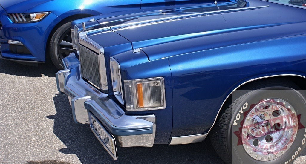 Blue classic car comparing with modern car | Blue classic car parked next to a modern Ford Mustang, showing automotive evolution design - Realisiert mit Pictrs.com