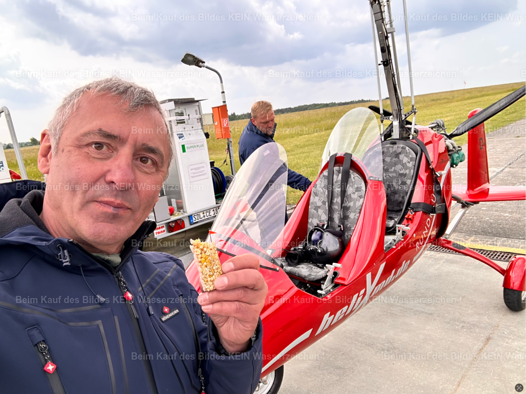 ich_vorm_Tragschrauber_in_Stendal_beim_Tanken | Danke. --- Wenn Sie bis hierher gelesen haben, haben Sie mich ein gutes Stück meines Lebens begleitet. --- Diese Galerie ist aus vielen Erinnerungen, unzähligen Stichworten und einer Menge gemeinsamer Arbeit mit ChatGPT entstanden. Erst beim Schreiben wurde mir selbst wieder bewusst, wie viele Menschen, Begegnungen und glückliche Zufälle meinen beruflichen Weg geprägt haben. Dieses Foto hier zeigt übrigens keinen besonderen Moment. Mein Pilot tankt gerade den Tragschrauber, ich esse einen Müsliriegel zum Mittag und kurze Zeit später geht es wieder in die Luft. Vielen Dank für Ihr Interesse - Steffen Lehmann - Realisiert mit Pictrs.com