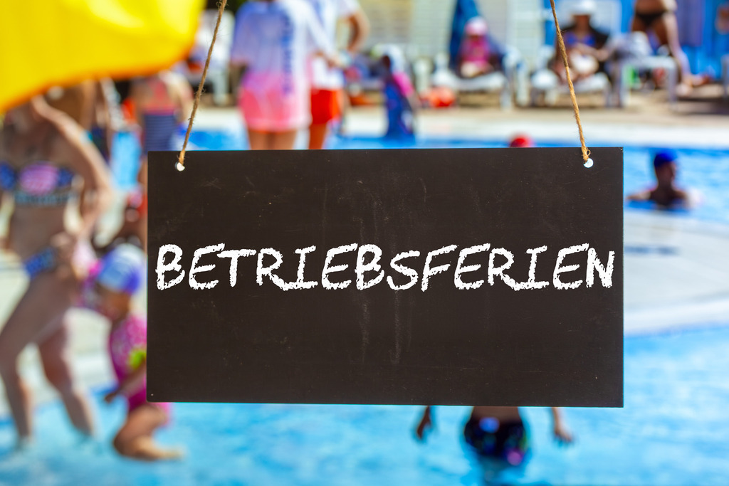 Symbolbild Betriebsferien: Schild mit der Aufschrift BETRIEBSFERIEN vor Sommerurlaubern im Freibad (Composing) | Symbolbild Betriebsferien: Schild mit der Aufschrift BETRIEBSFERIEN vor Sommerurlaubern im Freibad (Composing) - Realisiert mit Pictrs.com