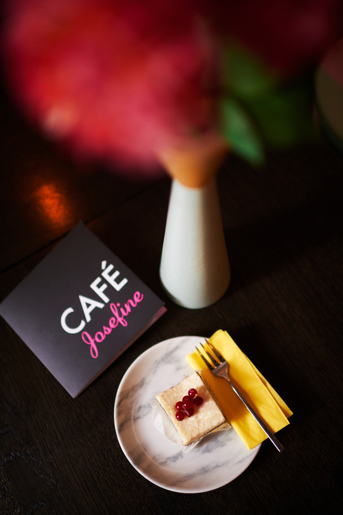 Cafe Josefine | WIen, Austria - February 13, 2018: Cafe Josefine; auf dem Tisch stehend eine Topfen-Mohn Schnitte mit Beeren, eine Speisekarte und eine Vase mit Blumen. - Realisiert mit Pictrs.com