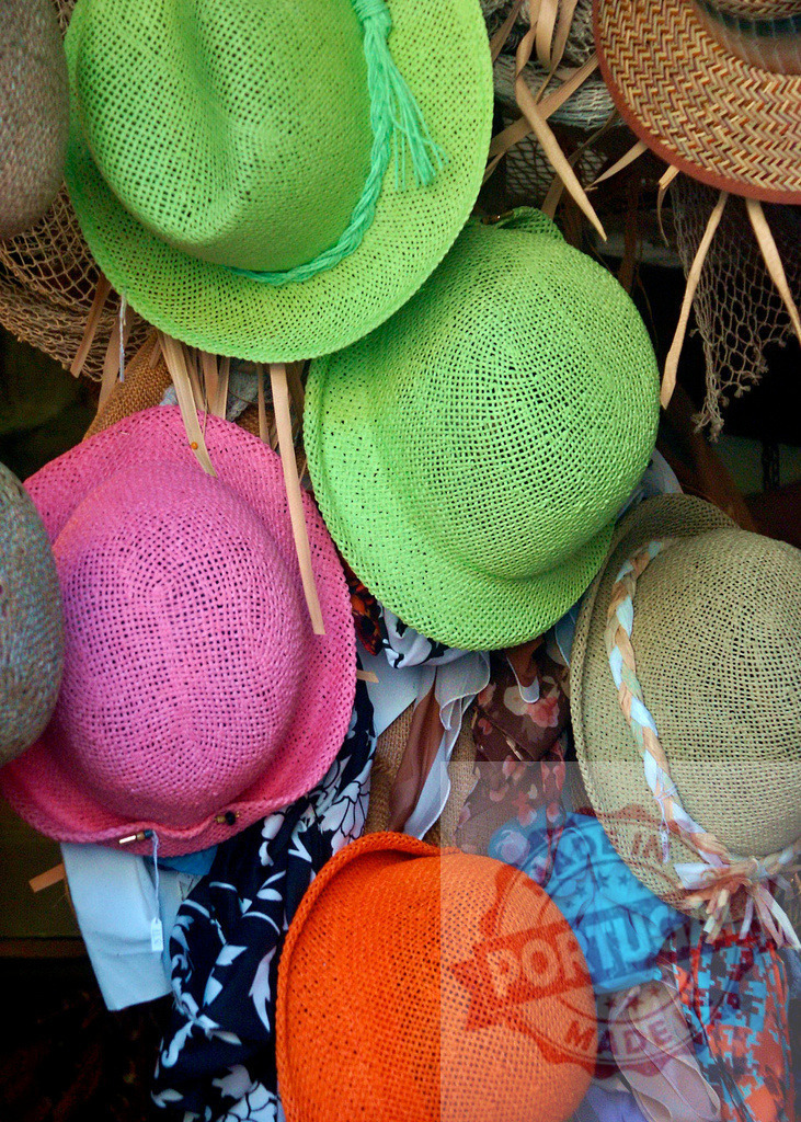 Colorful straw hats hanging for sale at market | Straw hats displaying vibrant colors hanging at an outdoor market stall - Realisiert mit Pictrs.com