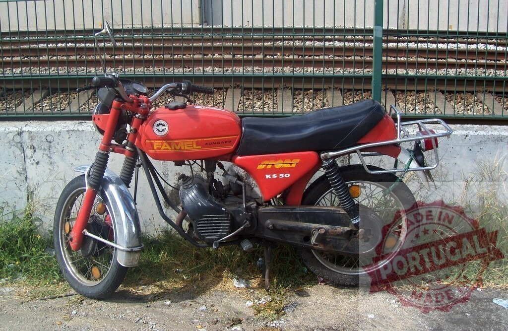 Red Famel KS50 Motorcycle Parked near Railroad Tracks | Vintage red Famel KS50 motorcycle parked near railroad tracks, evoking a sense of nostalgia and adventure - Realized with Pictrs.com