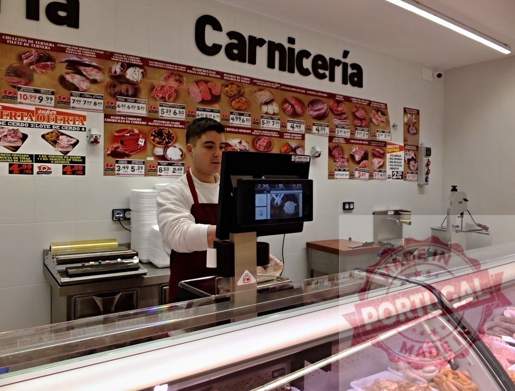 Butcher weighing fresh meat on scale in carniceria | Butcher working at a meat counter, weighing various fresh meat products for sale - Realisiert mit Pictrs.com