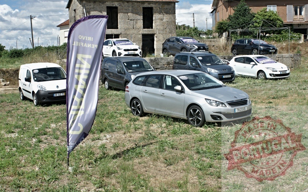 Used cars for sale in outdoor dealership lot | Used cars parked on a grassy outdoor lot with an advertising banner - Realized with Pictrs.com