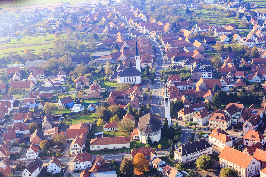 Aerial view: Two churches in the village center in Hatten in the state Bas-Rhin, France. – Photo: IMG_075640.jpg taken on 11/01/2014 by Werner Riehm/FLY-FOTO.com – Resolution of the original: 5251 x 3501 px