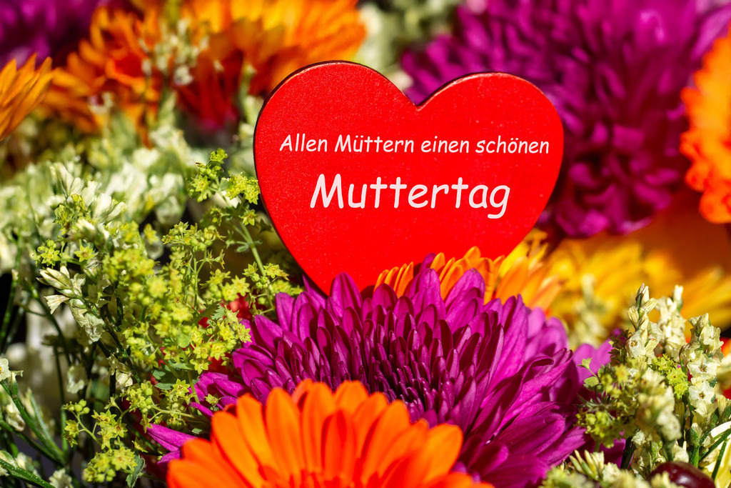 Muttertag 2025 - Allen Müttern einen schönen Muttertag | Blumenstrauß mit rotem Steckherz mit der Aufschrift ALLEN MÜTTERN EINEN SCHÖNEN MUTTERTAG - Realisiert mit Pictrs.com