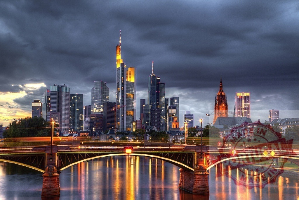 Frankfurt skyline at dusk with illuminating reflections | Frankfurt am Main cityscape with illuminated skyscrapers, bridge, and river reflecting evening lights under a cloudy sky - Realized with Pictrs.com