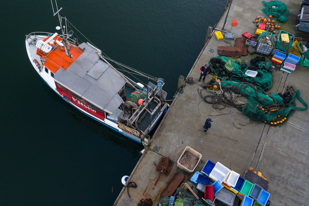 zeitenwende-farbe-03-21 | Christian Ross ist der jüngste unter den Fischern vom Holm in Schleswig an der Schlei. Er fischt am liebsten allein auf dem Kutter "Schle 26" auf der Ostsee. Bei dieser Luftaufnahme bereitet Christian Ross die Montage eines neuen Schleppnetzes am Liegeplatz des Schiffes im Hafen von Kappeln vor. - Realisiert mit Pictrs.com