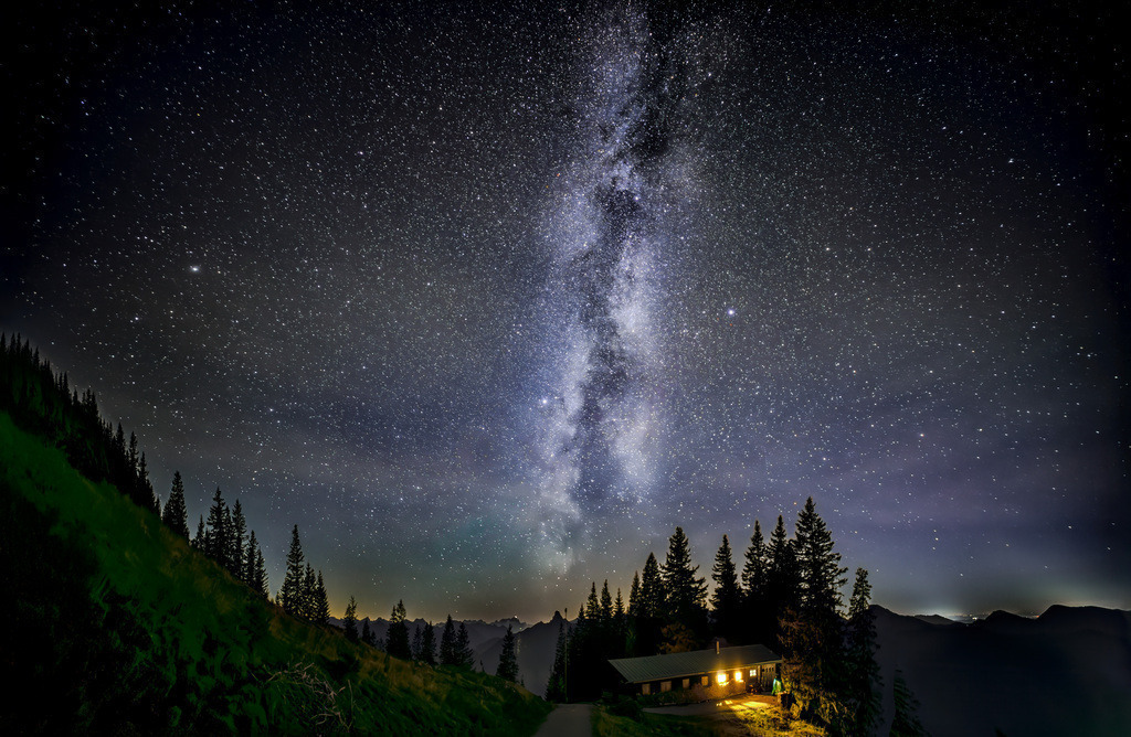 Die Milchstraße mit Sternenhimmel auf dem Wallberg am Tegernsee | Das Bild zeigt die Milchstraße, unsere Heimatgalaxie, die als helles Band am Nachthimmel erscheint. Die Milchstraße ist eine Spiralgalaxie, die aus schätzungsweise 100 bis 400 Milliarden Sternen besteht. Unser Sonnensystem befindet sich in einem der Spiralarme dieser Galaxie. Der Name leitet sich aus der griechischen Mythologie ab, in der das Band als ein verschütteter Strahl der Muttermilch der Göttin Hera gedeutet wurde.  - Realisiert mit Pictrs.com