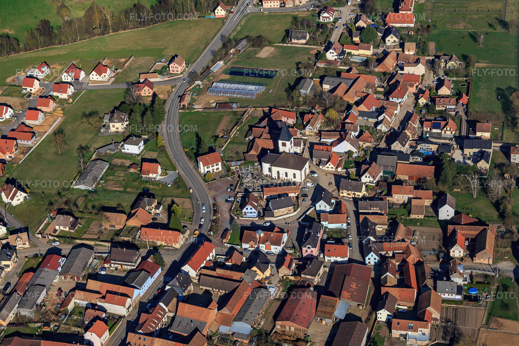 Aerial view: Church and cemetery in the village center in Lupstein in the state Bas-Rhin, France. – Photo: IMG_097566.jpg taken on 03/16/2017 by Werner Riehm/FLY-FOTO.com – Resolution of the original: 5209 x 3473 px