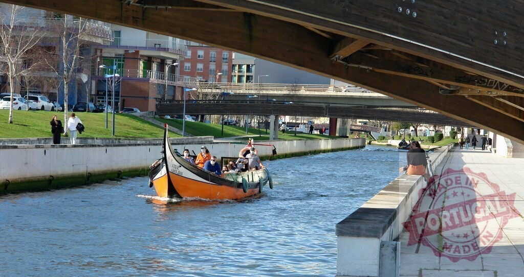 Moliceiro boat carrying tourists on Aveiro canal | People enjoying a traditional Moliceiro boat tour along a urban canal in Aveiro, Portugal - Realisiert mit Pictrs.com
