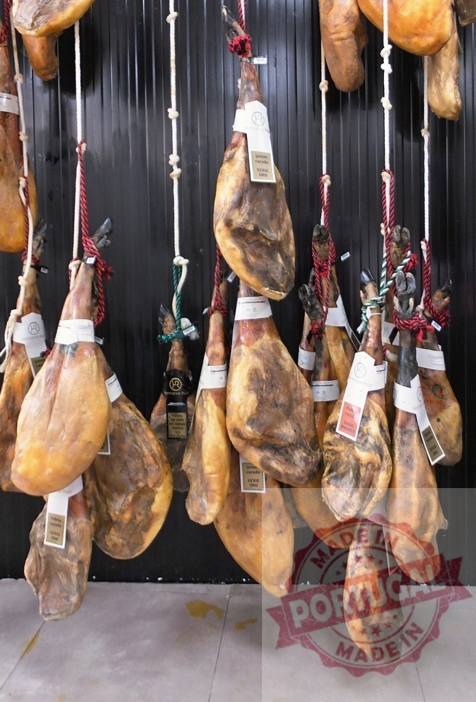 Spanish Jamón ibérico cured ham legs hanging for sale | Many Jamón ibérico legs hanging in a traditional deli store - Realisiert mit Pictrs.com