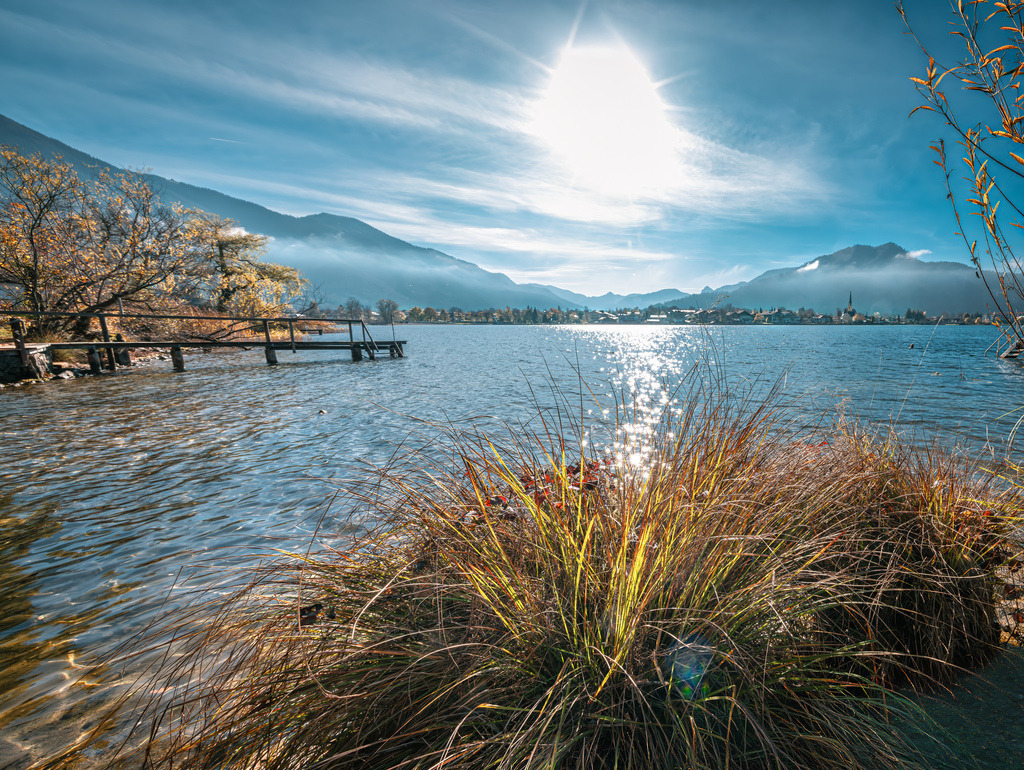 Malerischer Blick über das Ufer des Tegernsee's, Holzsteg im Wasser | Das Bild zeigt das malerische Ufer des Tegernsees in Oberbayern mit Blick auf die umliegenden Alpen und einen kleinen Holzsteg - Realisiert mit Pictrs.com