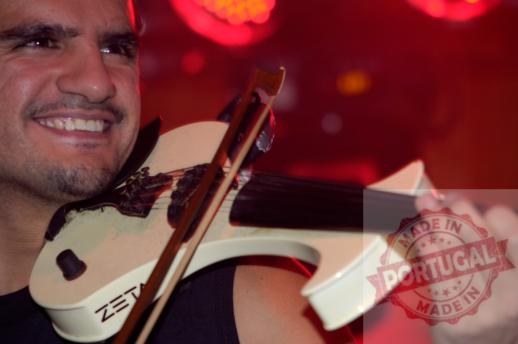 Musician playing electric violin during live performance on stage | Musician smiling while playing electric violin during live performance on stage - Realized with Pictrs.com
