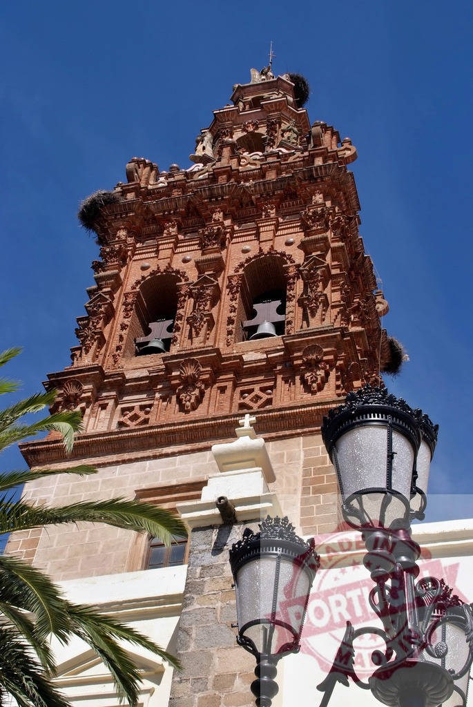 San Bartolome church bell tower with storks. Extremdura - Spain | Ornate bell tower of San Bartolome church with storks nesting under a clear blue sky - Realisiert mit Pictrs.com