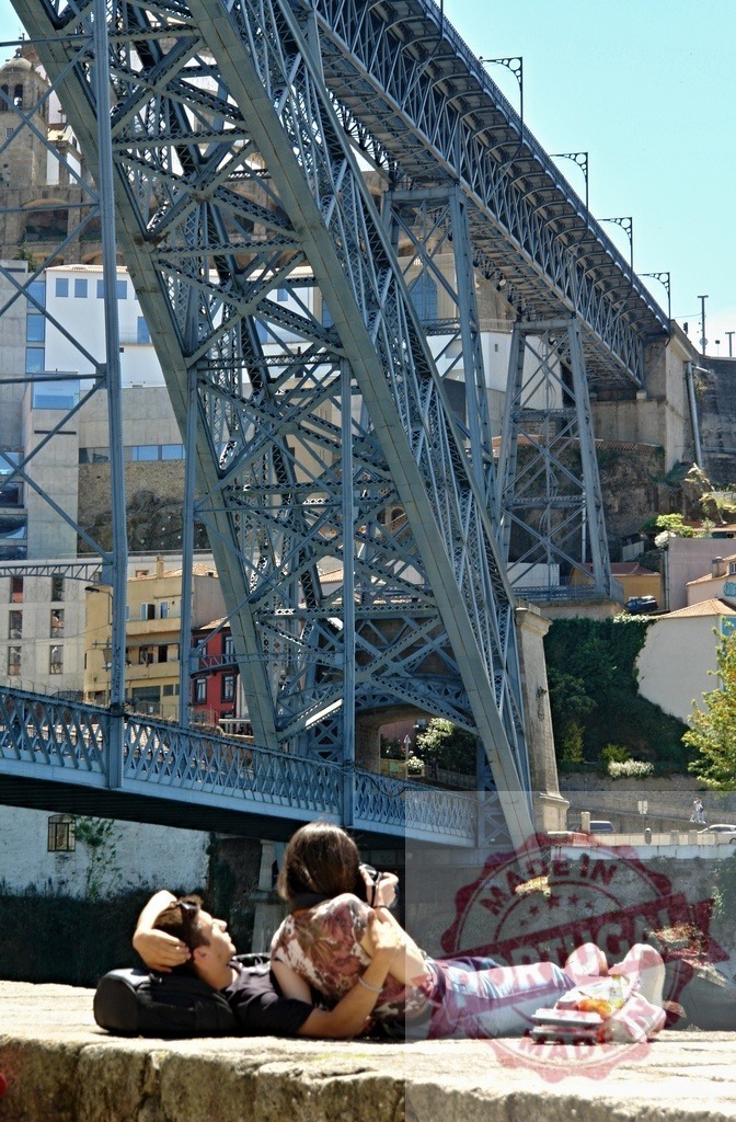 Couple relaxing under Dom Luís I Bridge in Porto | Young couple enjoying leisure time on a sunny day in Porto, Portugal - Realized with Pictrs.com