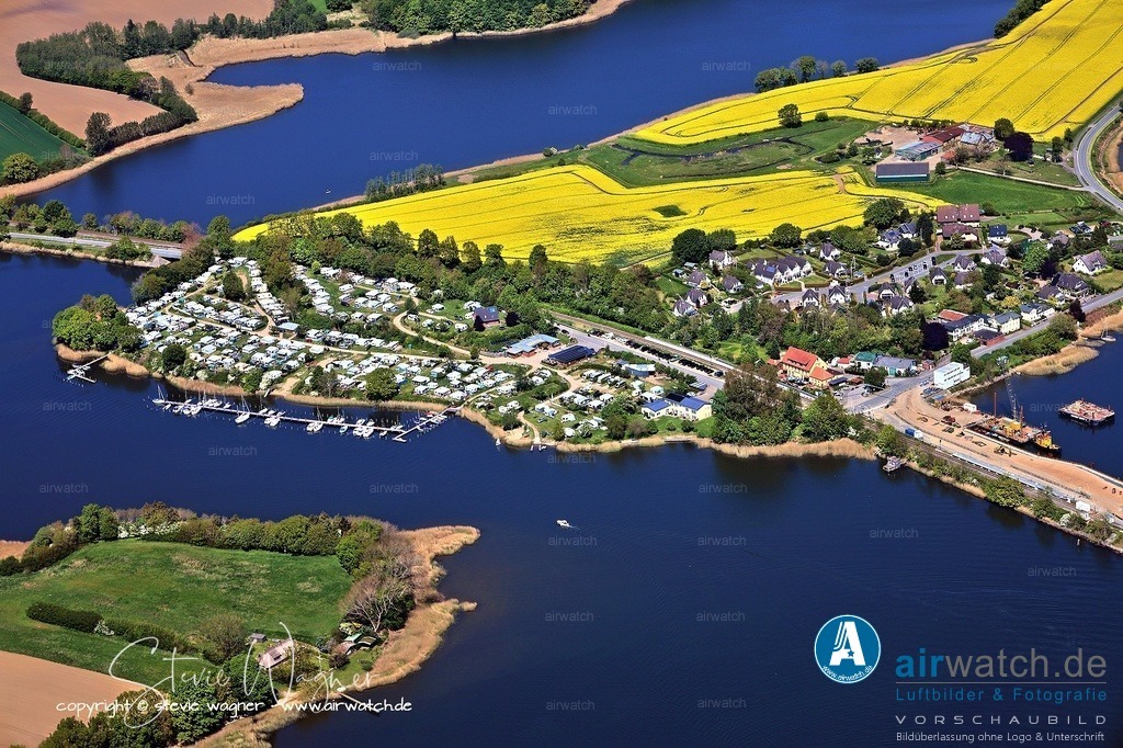 Luftbild Ostseefjord Schlei, Boren-Lindaunis Schleibrücke, Campingplatz Lindaunis, Sportboothafen Lindaunis | Der Campingplatz Lindaunis liegt mitten im Naturpark Schlei im hohen Norden Deutschlands und bietet eine idyllische Lage inmitten von Natur mit Nähe zum Wasser. Er ist gut eine Autostunde nördlich von Hamburg gelegen und eignet sich für Gäste, die Ruhe, frische Luft und direkten Zugang zur Schleilandschaft suchen. Angeboten werden Stellplätze für Zelte, Wohnmobile und Wohnwagen, wobei der Fokus auf einem naturnahen und entspannten Aufenthalt liegt.