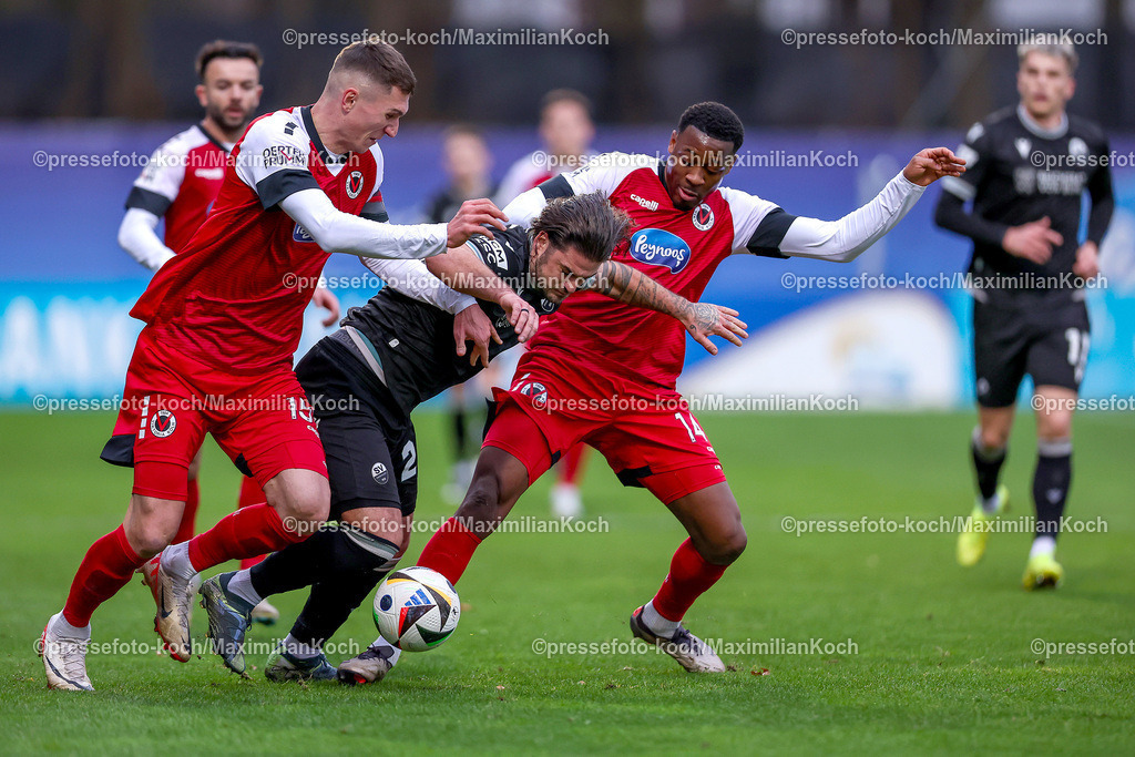 FCVK21122401026 | 21.12.2024, Fußball, FC Viktoria Köln – SV Sandhausen, 3.Liga, Sportpark Höhenberg, Saison 2024 2025: Christoph Greger (Viktoria Köln #15) und Enrique Lofolomo (Viktoria Köln #14) im Zweikampf gegen Dominic Baumann (Sandhausen #28)DFB regulations prohibit any use of photographs as image sequences and or quasi-video.
