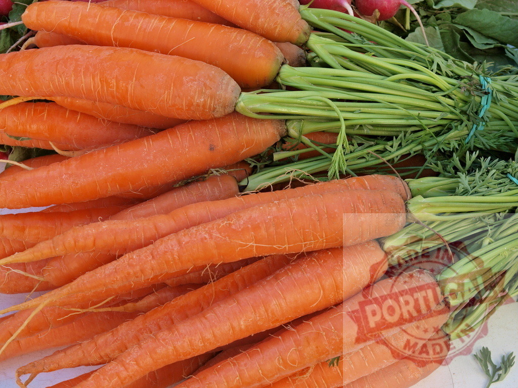 Fresh organic carrots with green tops at market | Fresh harvested organic carrots displayed with vibrant green tops at a local market - Realized with Pictrs.com