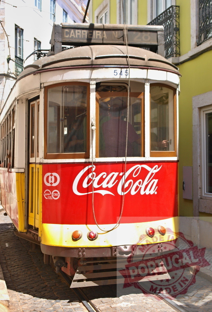 Vintage Lisbon tram running on cobblestone street with Coca-Cola advertisement | Red and yellow vintage Lisbon tram running on cobblestone street with Coca-Cola advertisement - Realized with Pictrs.com