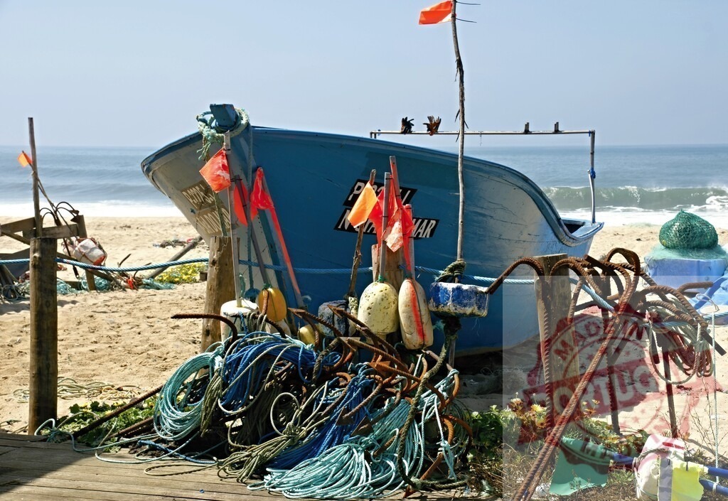 Fishing boat and gear on sand beach by ocean | Blue fishing boat resting on a sandy beach with fishing ropes, buoys, and anchors - Realized with Pictrs.com