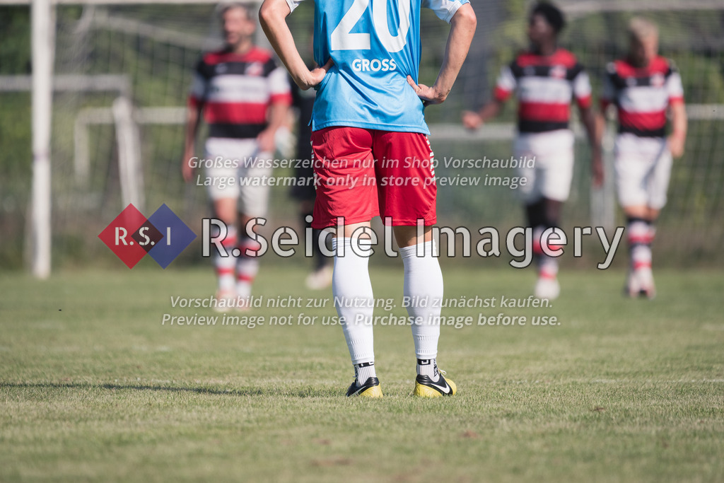RS-1-126693 | Fußballler in hellblauem Trikot, roten Shorts, weißen Stutzen und schwarz-gelben Nike Schuhen steht auf dem Rasen und stemmt wartend die Hände in die Hüften.